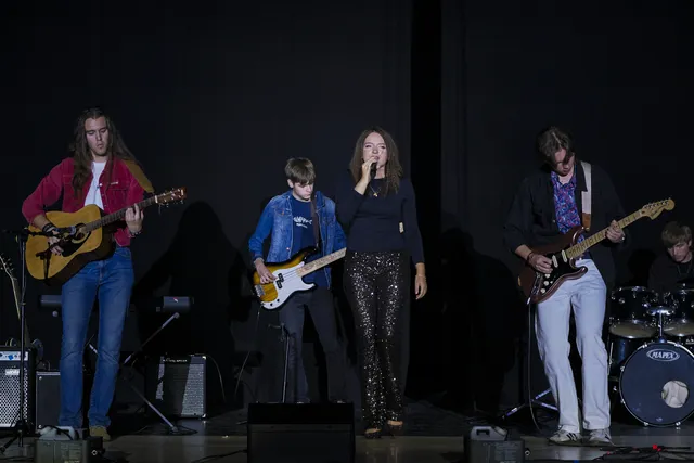 Zespół z wokalistką, gitarami i perkusją na scenie auli przy Wodnej 34